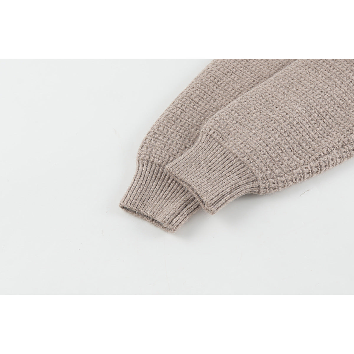 Close-up of a taupe cardigan sleeve and ribbed cuff, showing the raised knit texture.