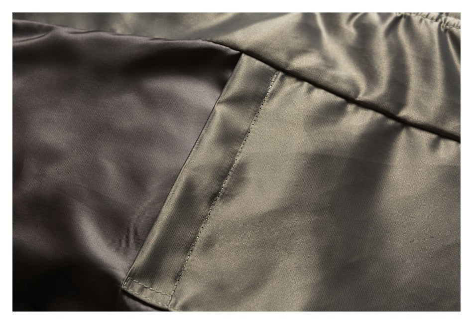 Close-up of a charcoal-olive garment panel with a stitched rectangular pocket edge and smooth lining.