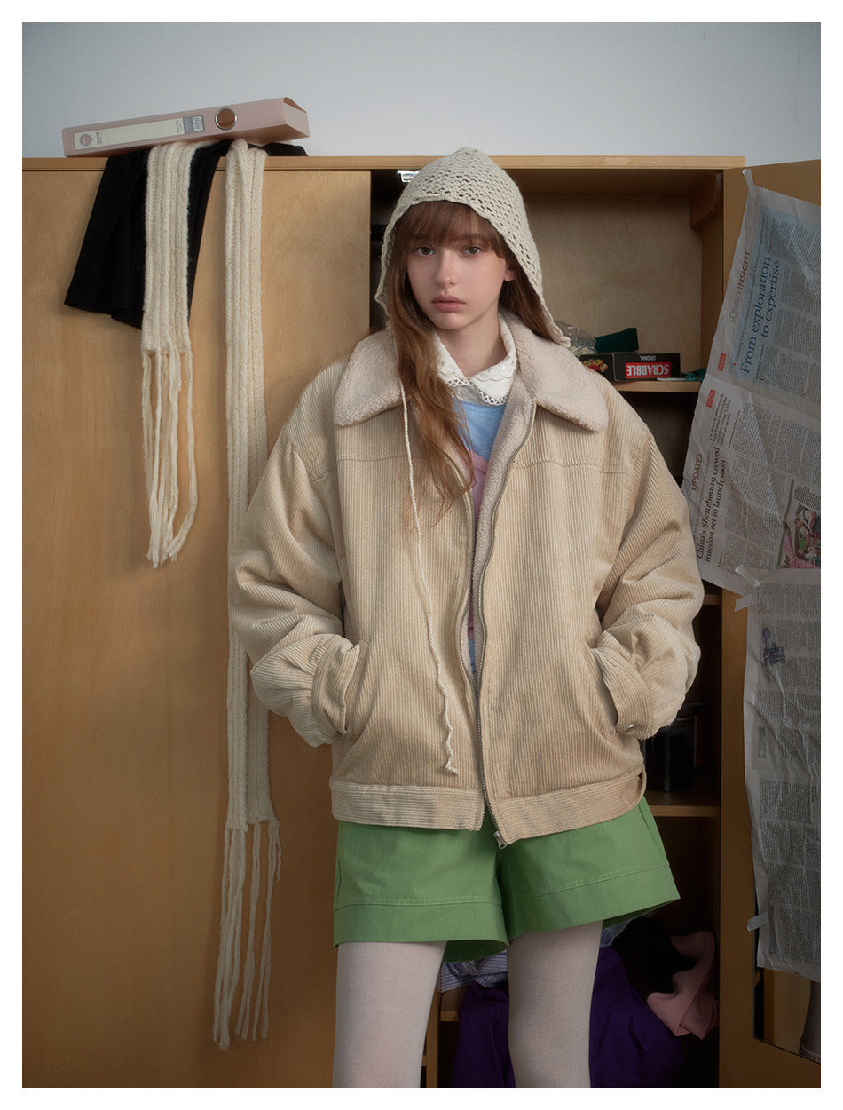 Front view of a model in a beige sherpa-collar jacket, cream knit hood, green shorts, and white tights.