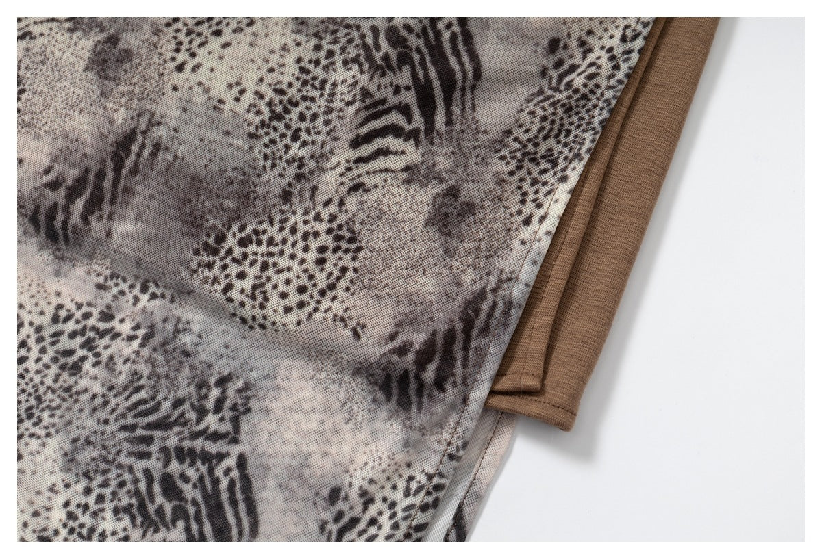 Close-up of gray-brown animal-print fabric beside a brown trim edge and stitched seam.