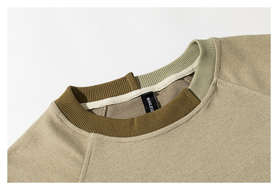 Close-up of a beige sweatshirt neckline with a brown ribbed collar and contrasting olive trim behind it.