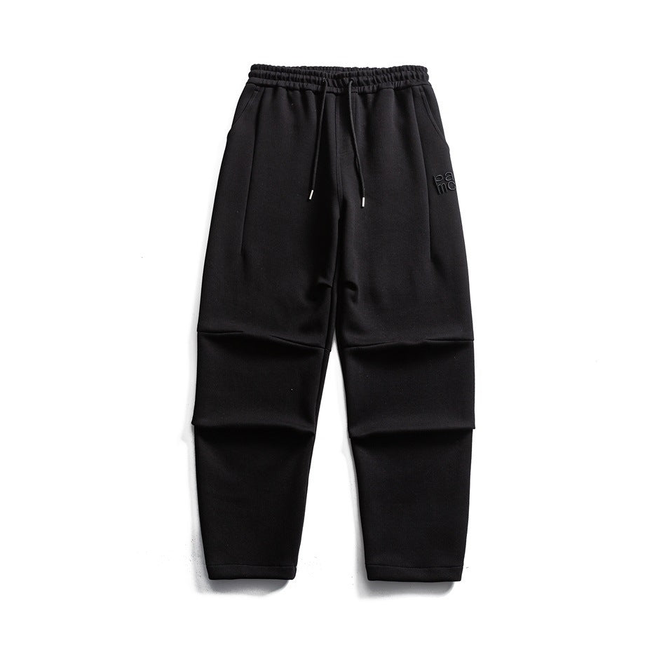 Black knit drawstring sweatpants flat lay with knee pleats and side pockets