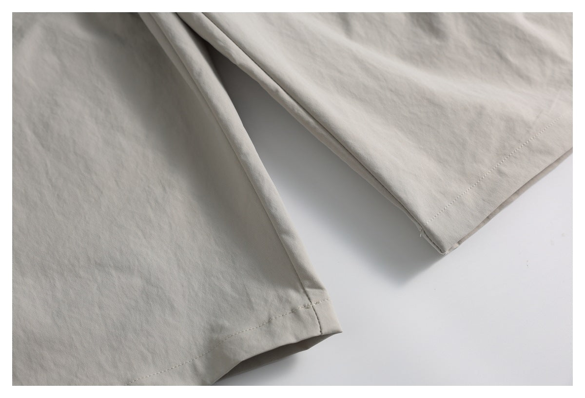 Close-up of two light taupe garment hems with visible stitching and folded fabric.