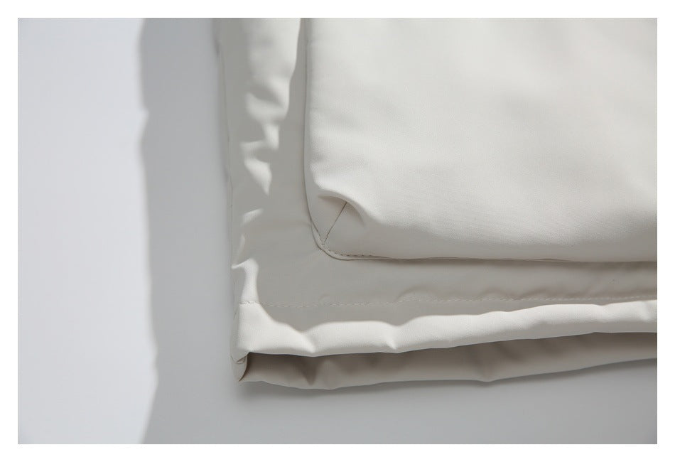 Close-up of an ivory jacket’s lower hem and the corner of a large pocket.