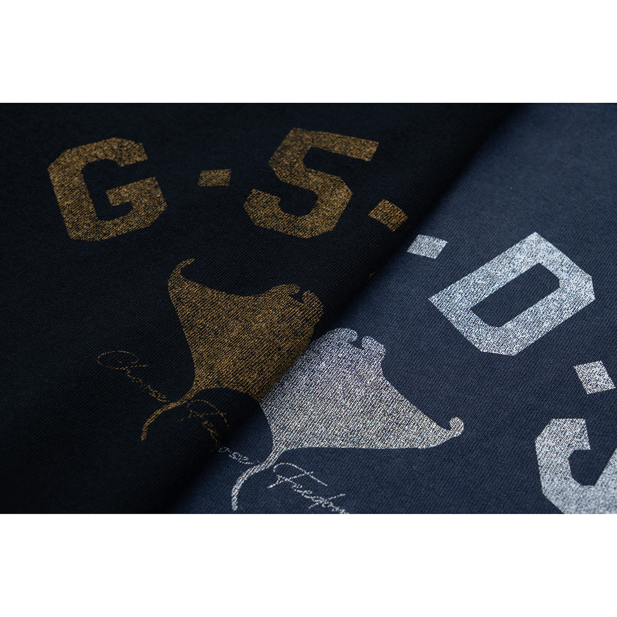 Close-up of distressed gold and white graphic lettering printed on dark T-shirt fabric.
