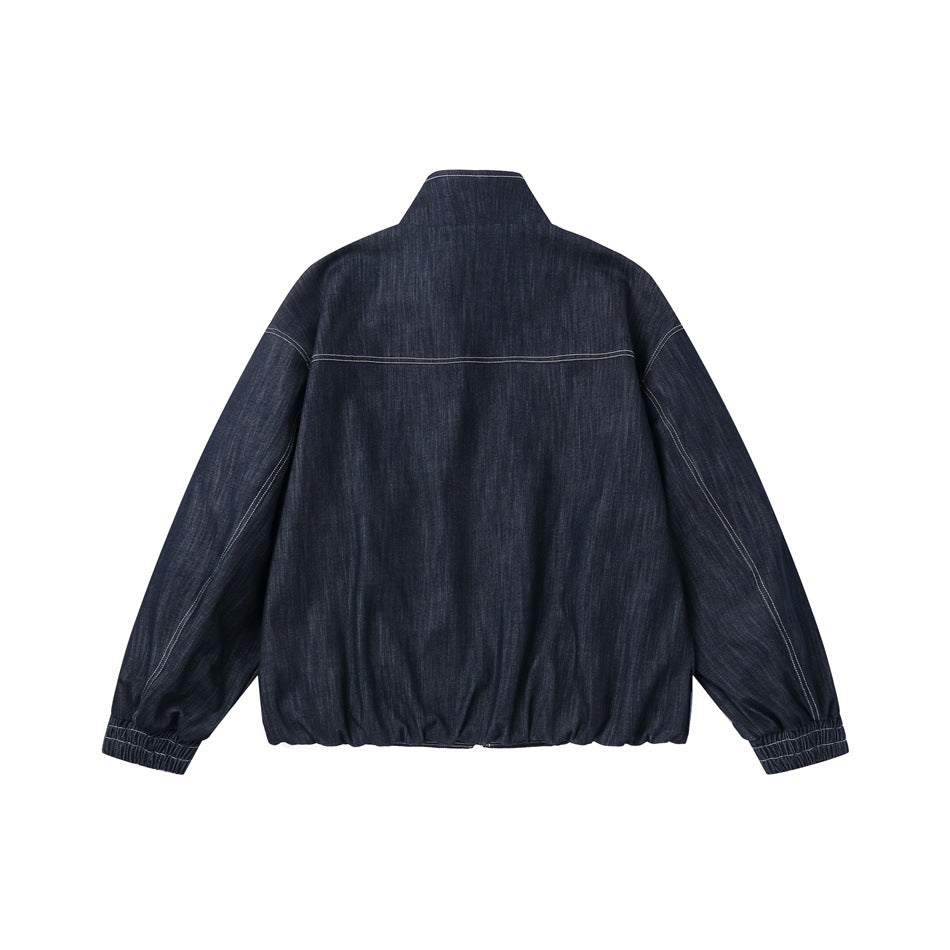 Back view of dark indigo denim jacket with stand collar, yoke seam, contrast stitching, elastic cuffs and gathered hem