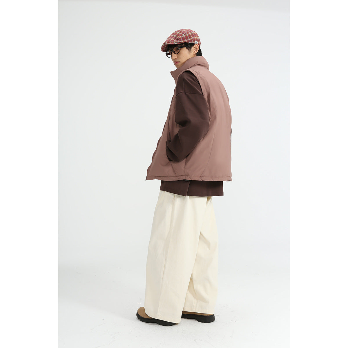 Model wears a dusty mauve high-collar vest over a brown top, shown from a rear three-quarter angle with cream wide-leg pants.
