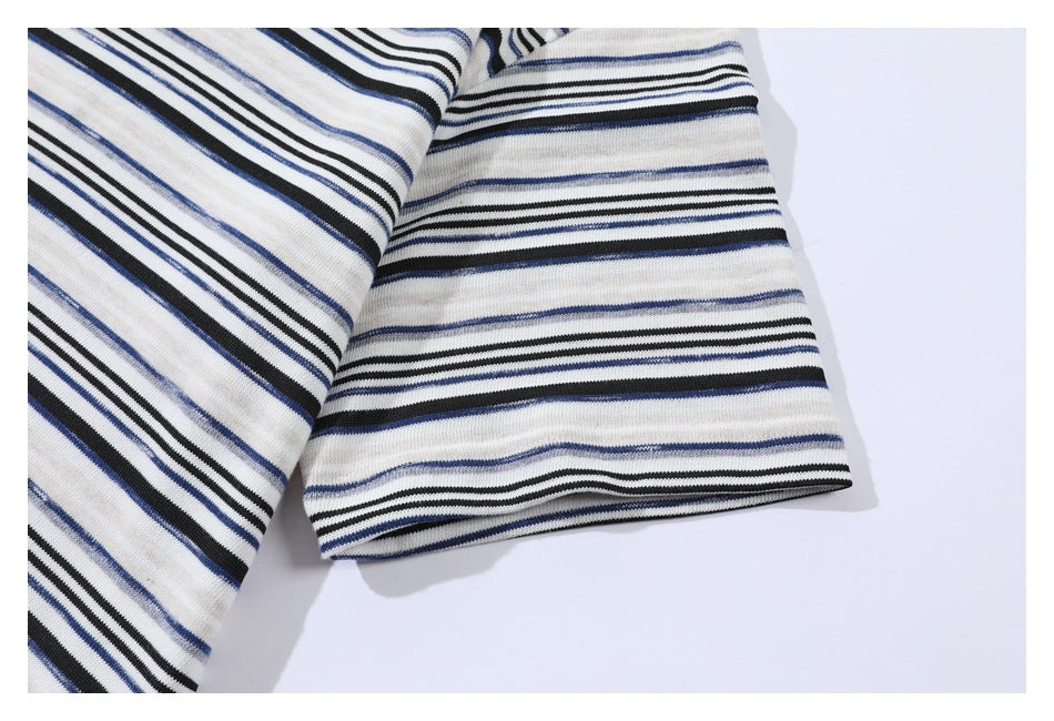 Close-up of a short sleeve on a cream shirt with black and blue horizontal stripes.