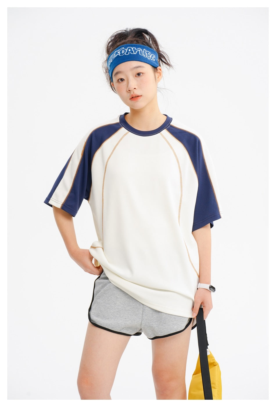 Closer view of an ivory raglan T-shirt with navy sleeves, a crew neck, and curved contrast stitching.