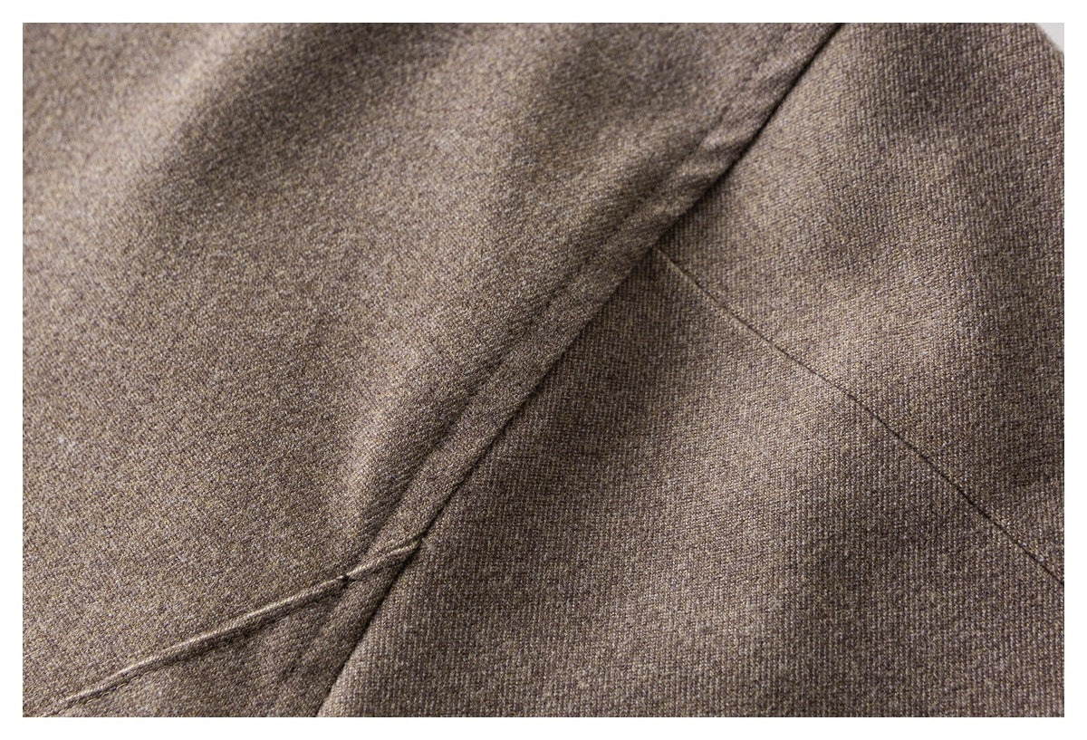 Close-up of intersecting seams on brown textured coat fabric.
