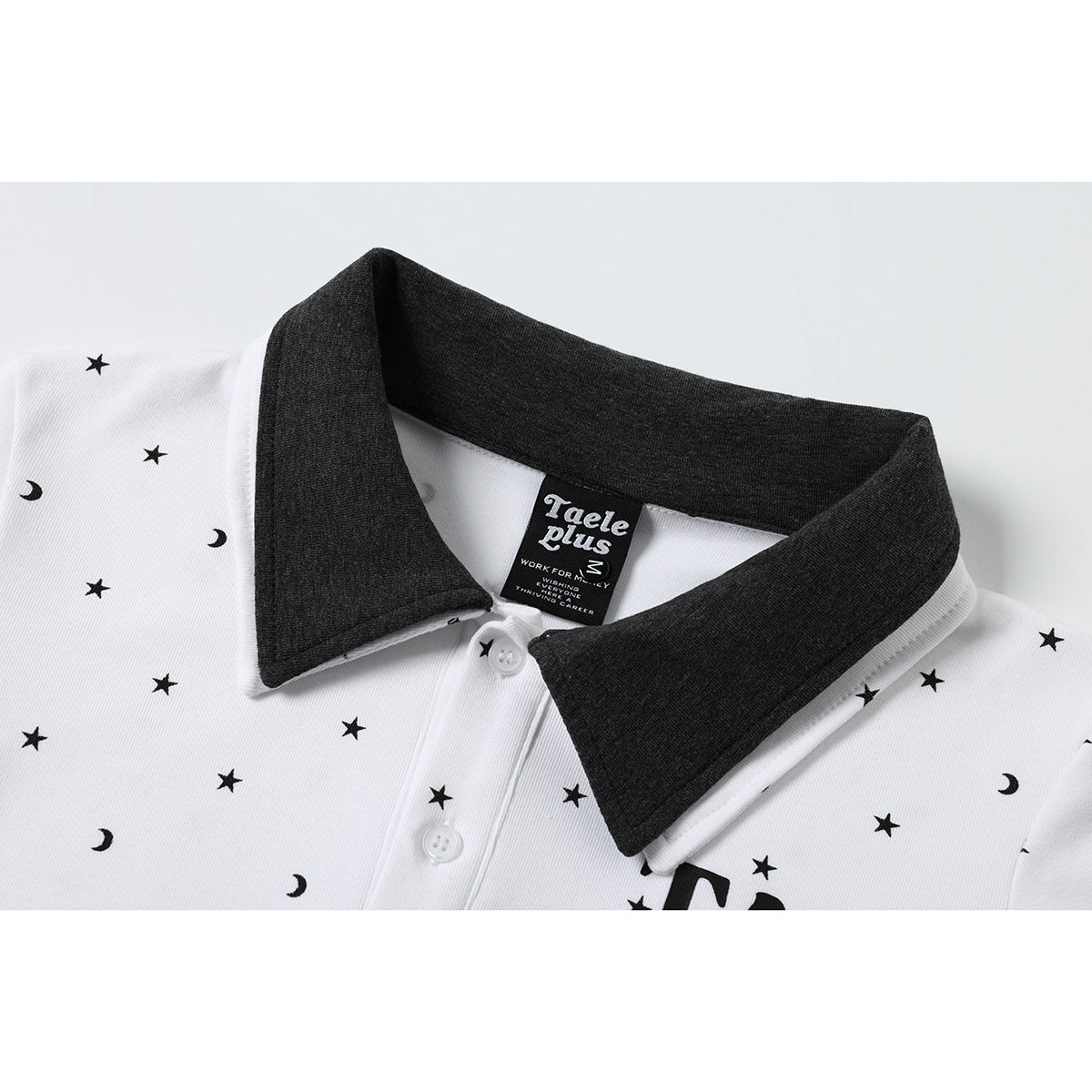 Close-up of a white polo shirt with a charcoal collar, moon-and-star print, buttons, and a sewn neck label.