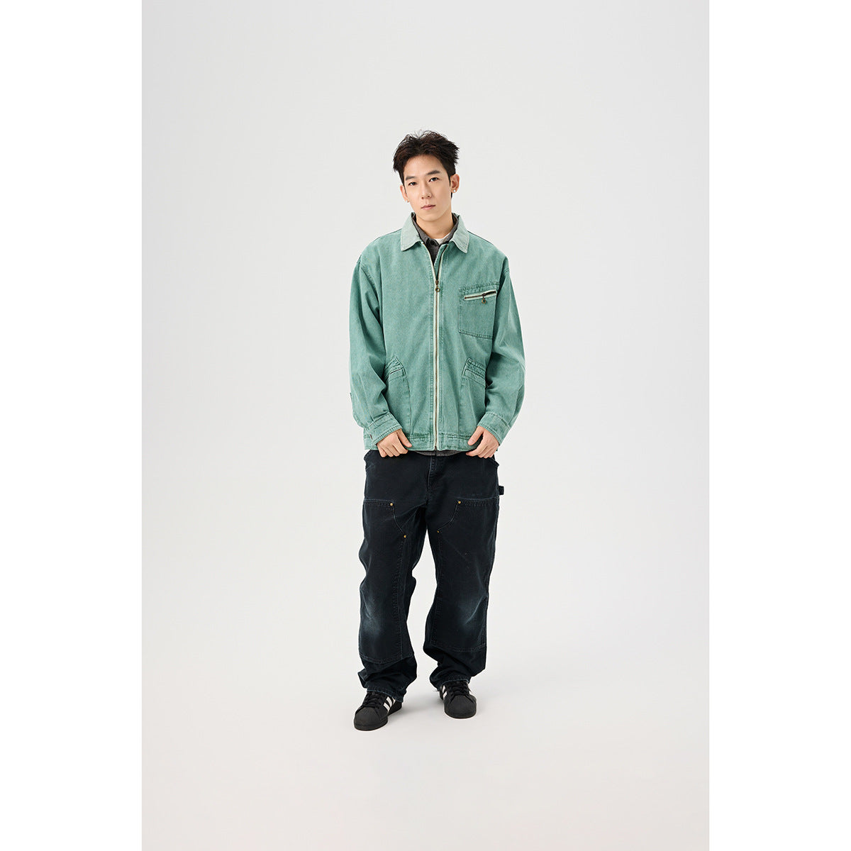 Full-length model wearing a faded teal zip-front jacket with multiple pockets and loose black pants.