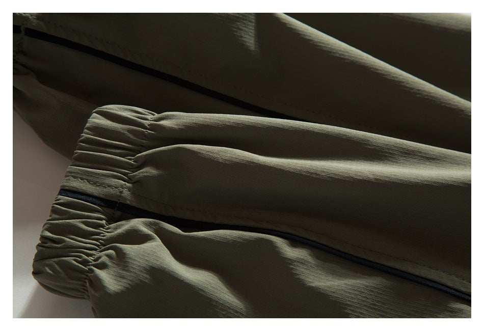 Close-up of an olive khaki sleeve with a gathered elastic cuff and black piping.