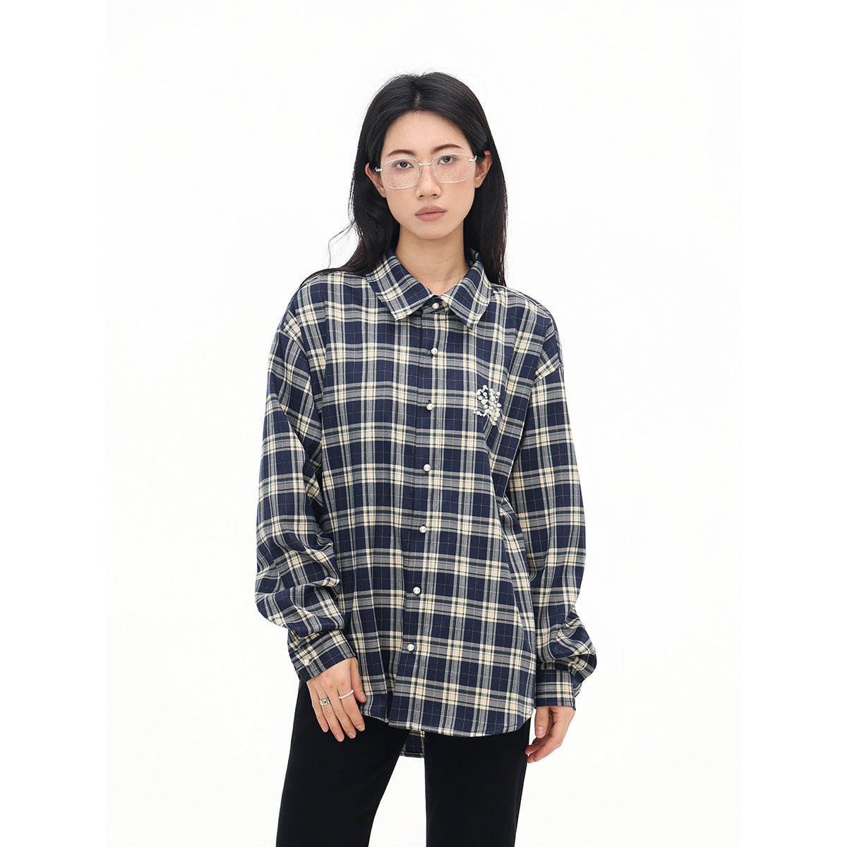 Closer view of a model in a navy and cream plaid button-up shirt with a beaded chest embellishment.