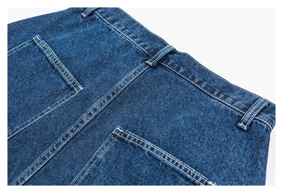Close-up of dark blue jeans showing the waistband, belt loops, seams, and back pockets.