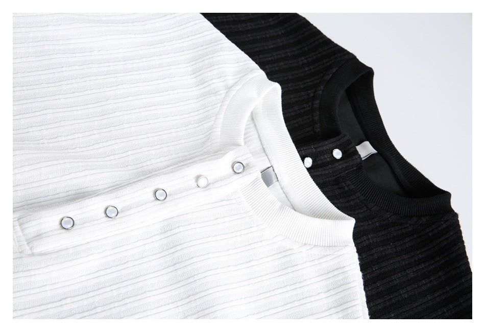 Close-up of white and black ribbed shirts showing their round necklines and snap-button plackets.