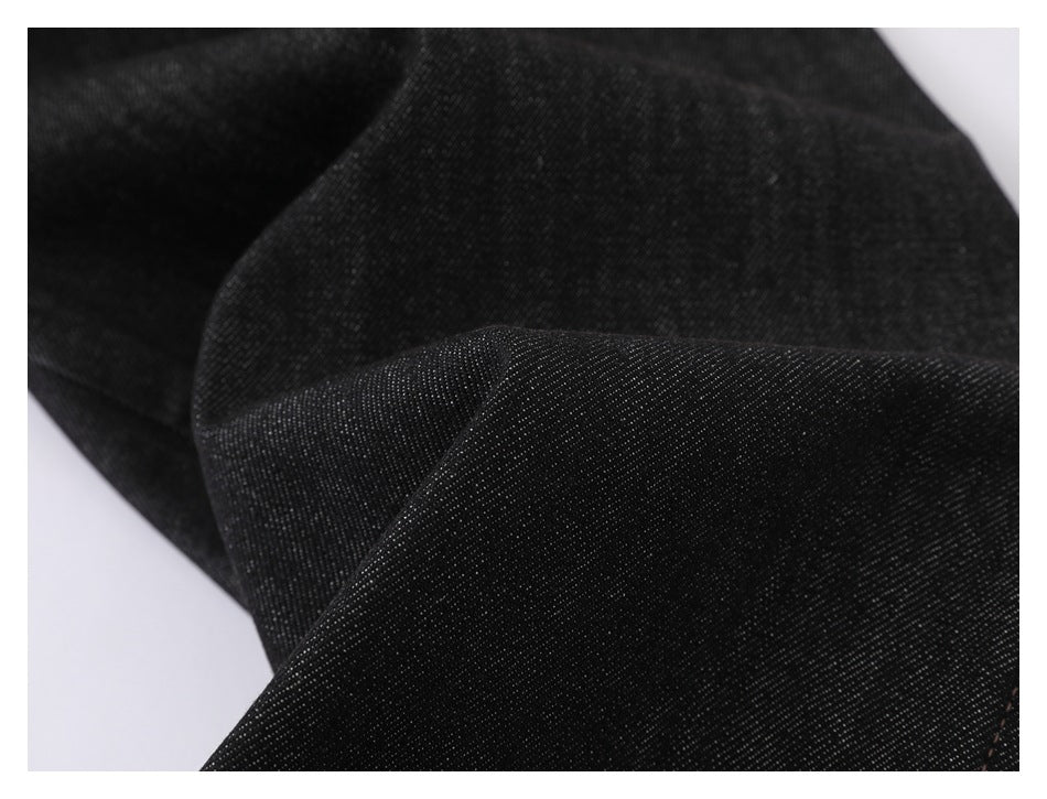 Close-up of folded black denim showing its diagonal weave and surface texture.