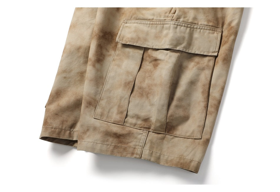 Close-up of tan mottled cargo shorts showing a large flap pocket and hemmed legs.