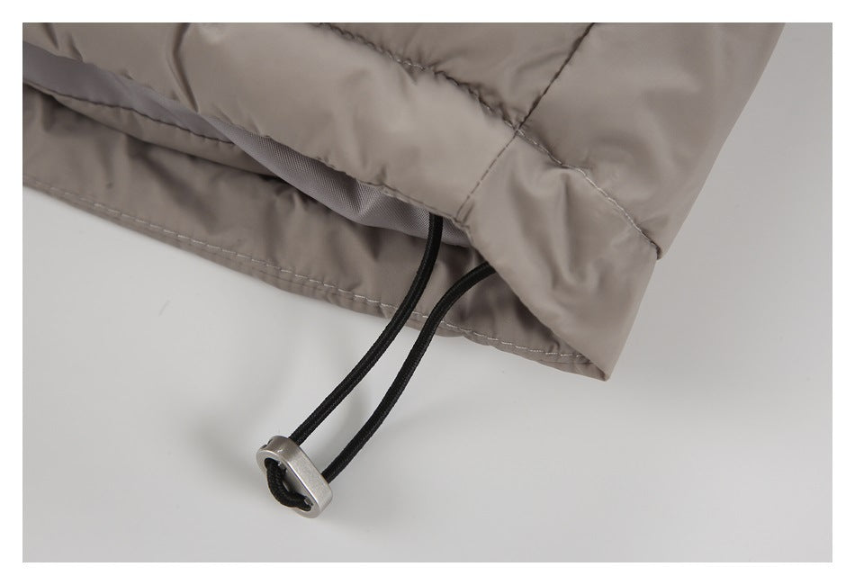 Close-up of a taupe jacket hem with a black drawcord and metal toggle.