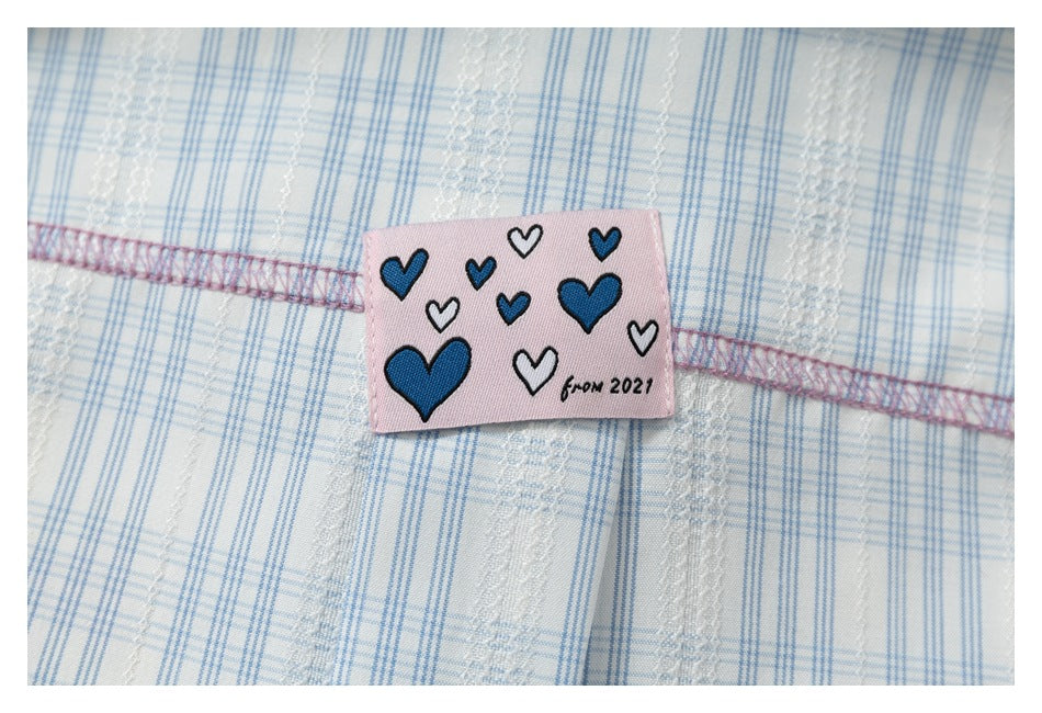 Pink sewn patch with blue and white hearts and “from 2021” on white and blue plaid fabric.