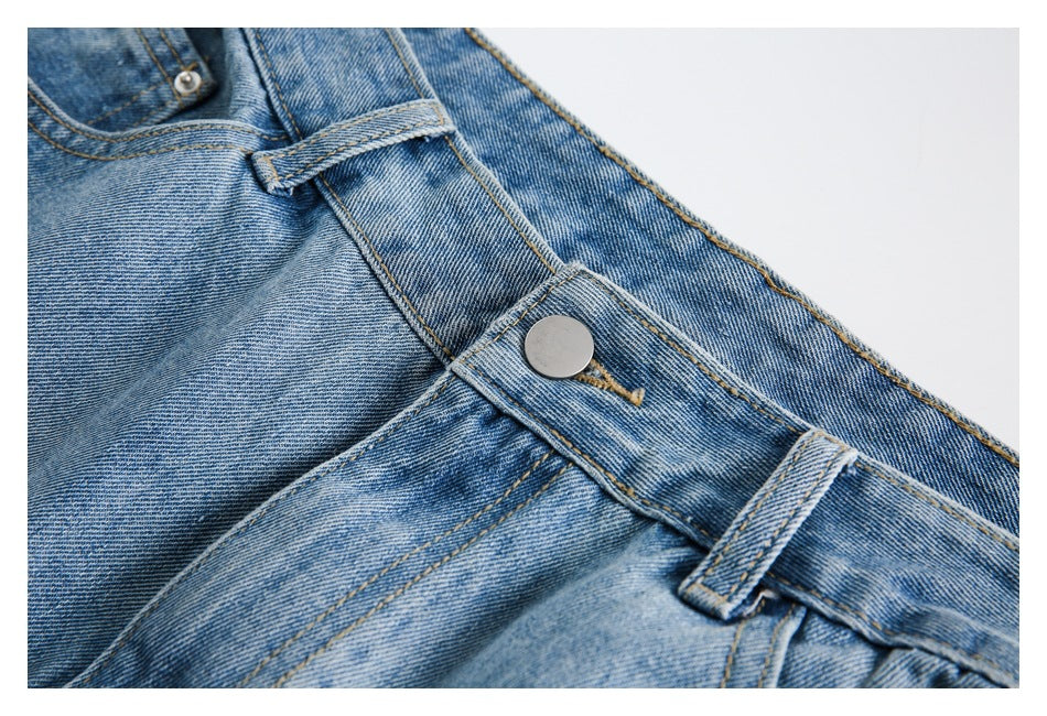 Close-up of the metal waist button and belt loops on faded blue denim shorts.