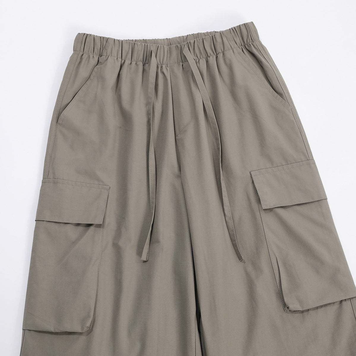 Front view of taupe-gray wide-leg cargo pants with an elastic waist, drawstring, and large flap pockets.