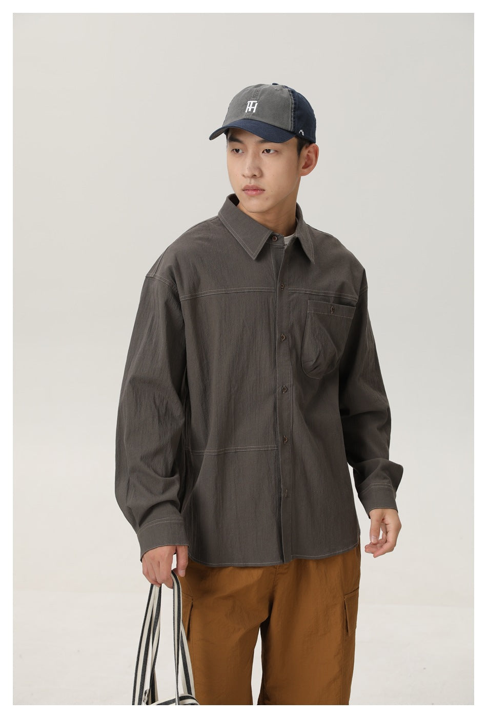 Front view of a man wearing a charcoal gray button-up shirt with a chest pocket and brown cargo pants.