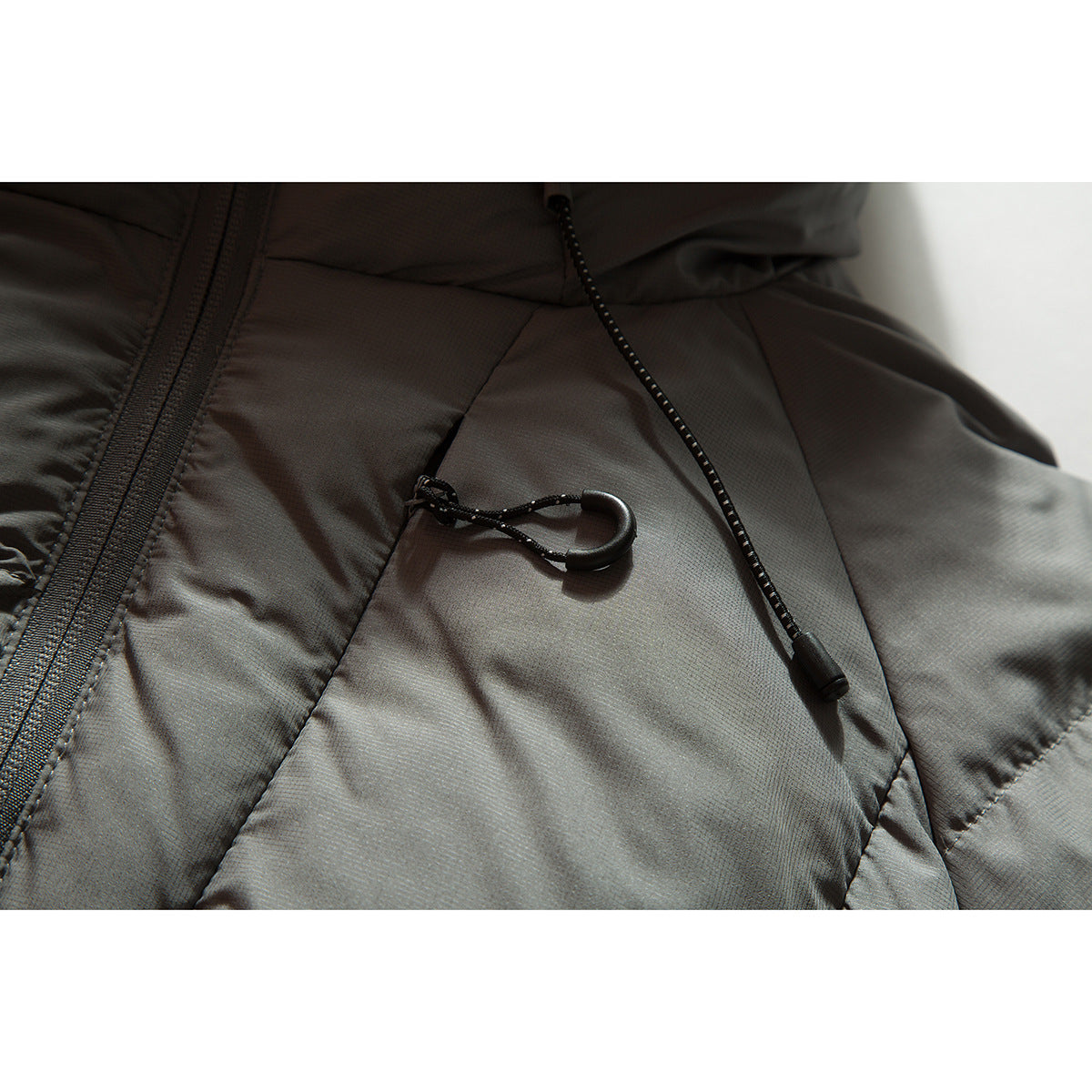Close-up of a charcoal gray puffer jacket with a front zipper and black drawcord toggles.