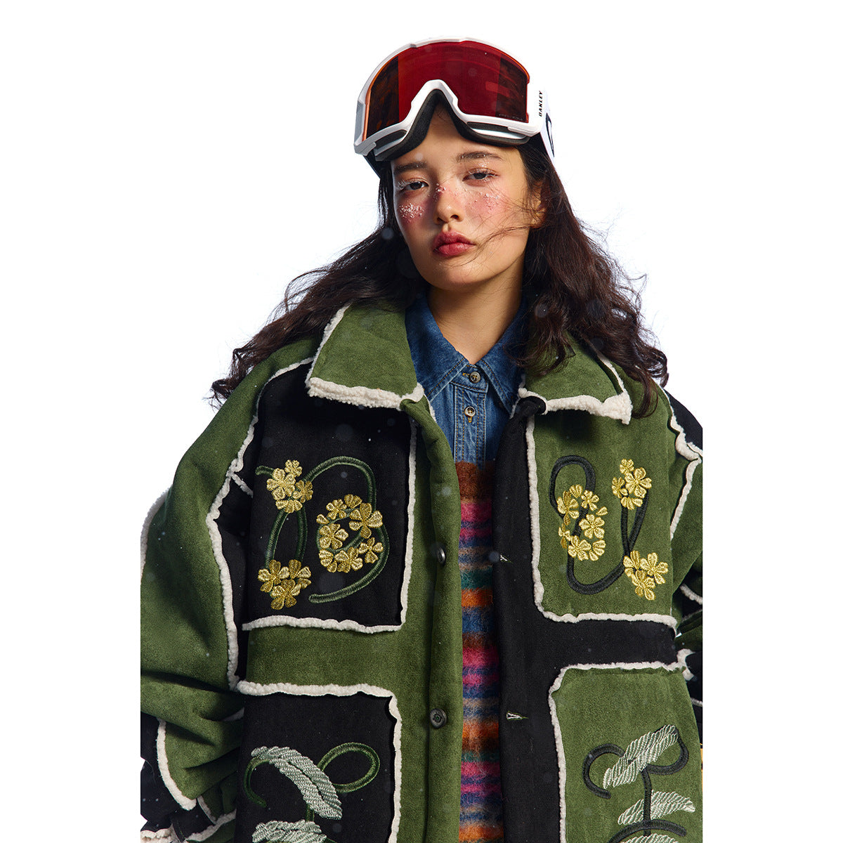 Closer front view of a model wearing a green and black jacket with cream trim and gold floral embroidery.