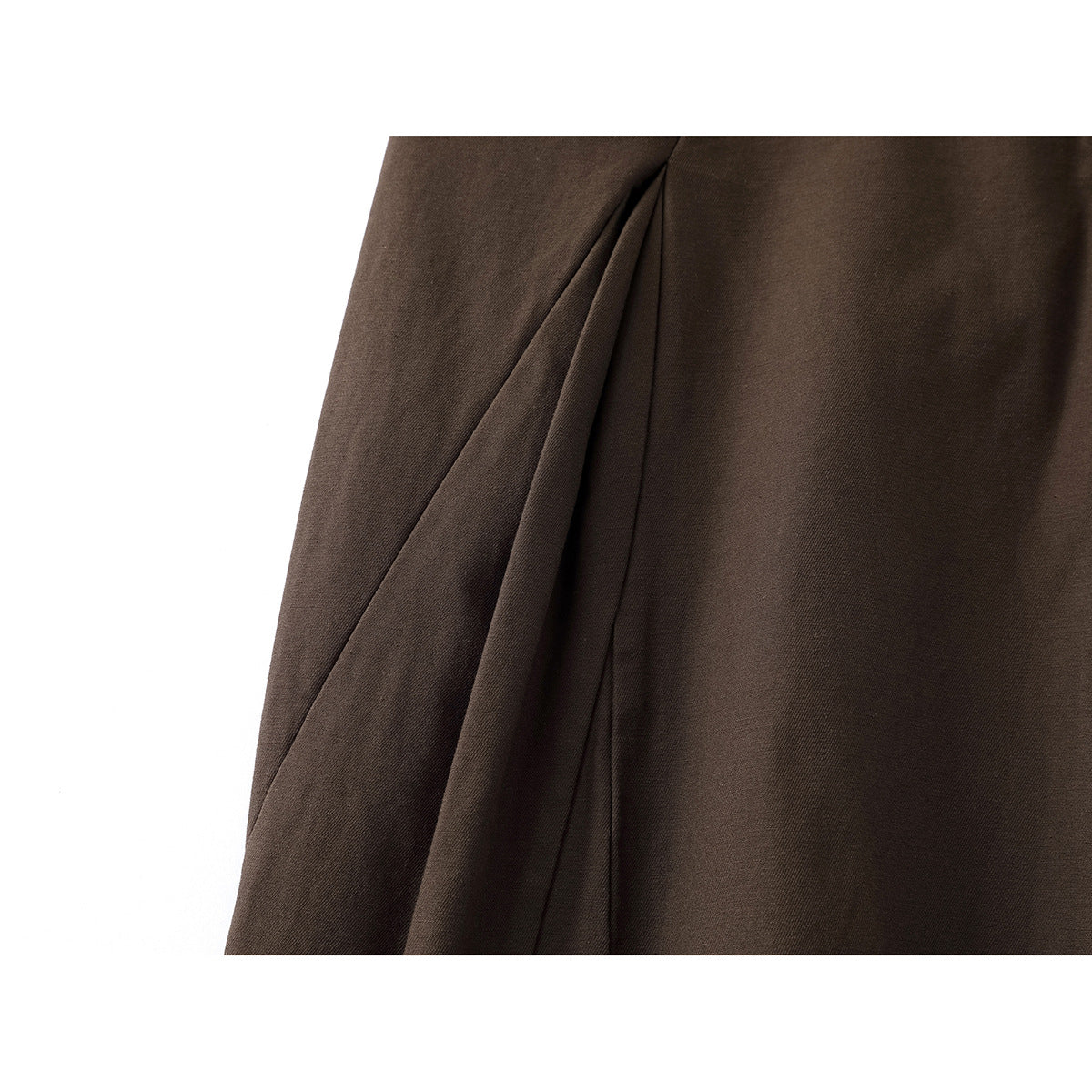 Close-up of dark brown pants showing a deep front pleat and seam.