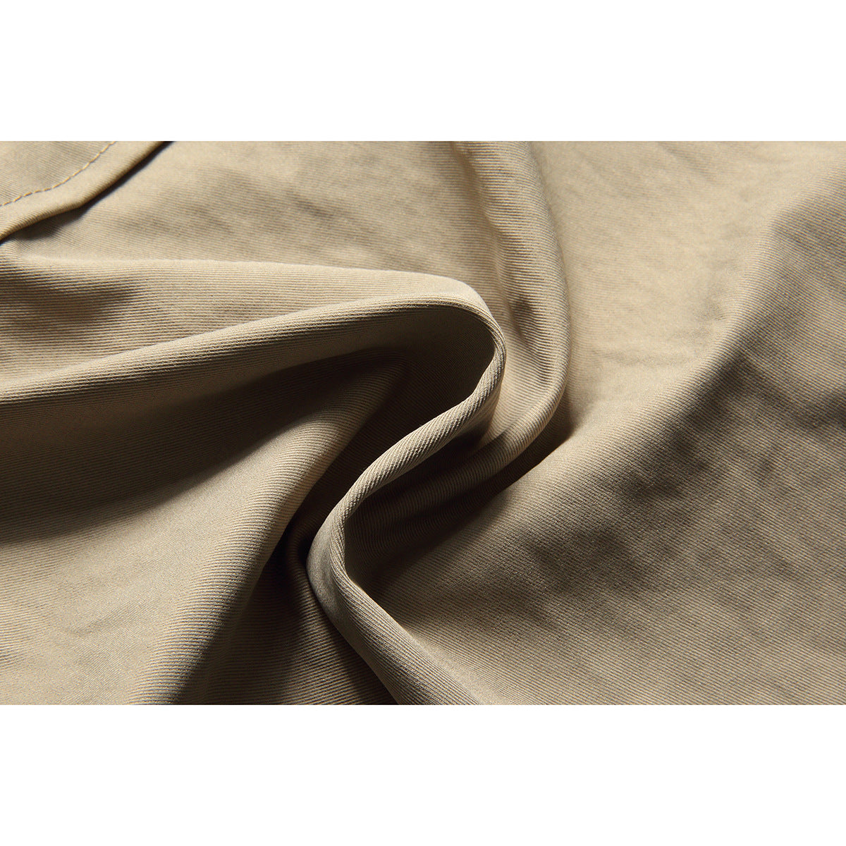 Close-up of beige fabric draped in folds, showing its fine surface texture.