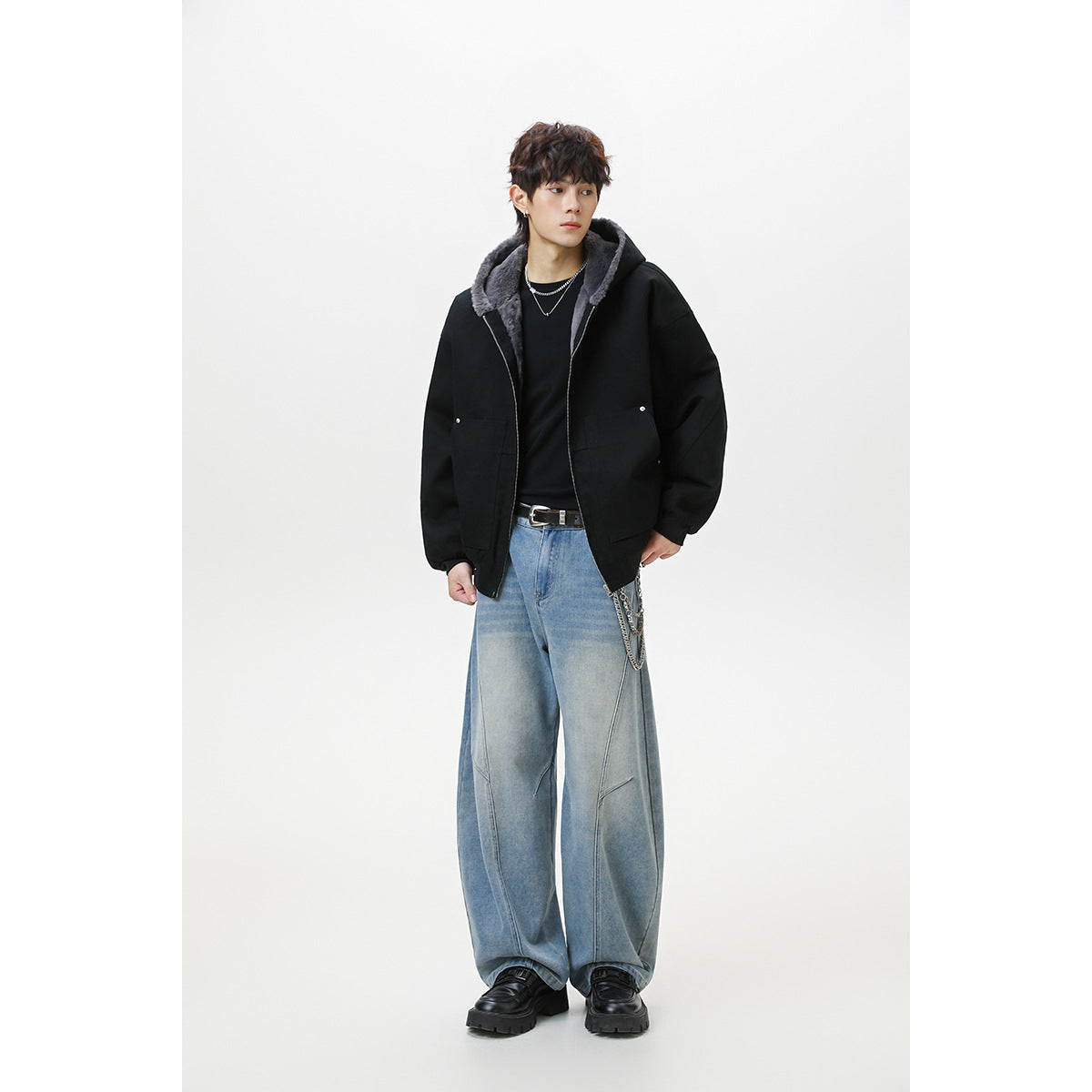 Full-length model wearing a black hooded jacket with gray plush lining, wide light-wash jeans, and black shoes.