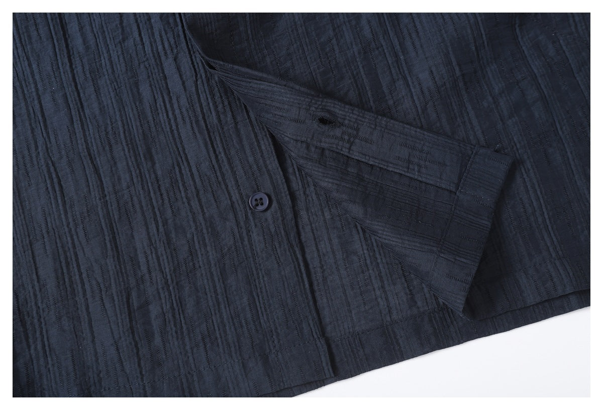Close-up of a dark navy garment hem with a button and folded fabric detail.