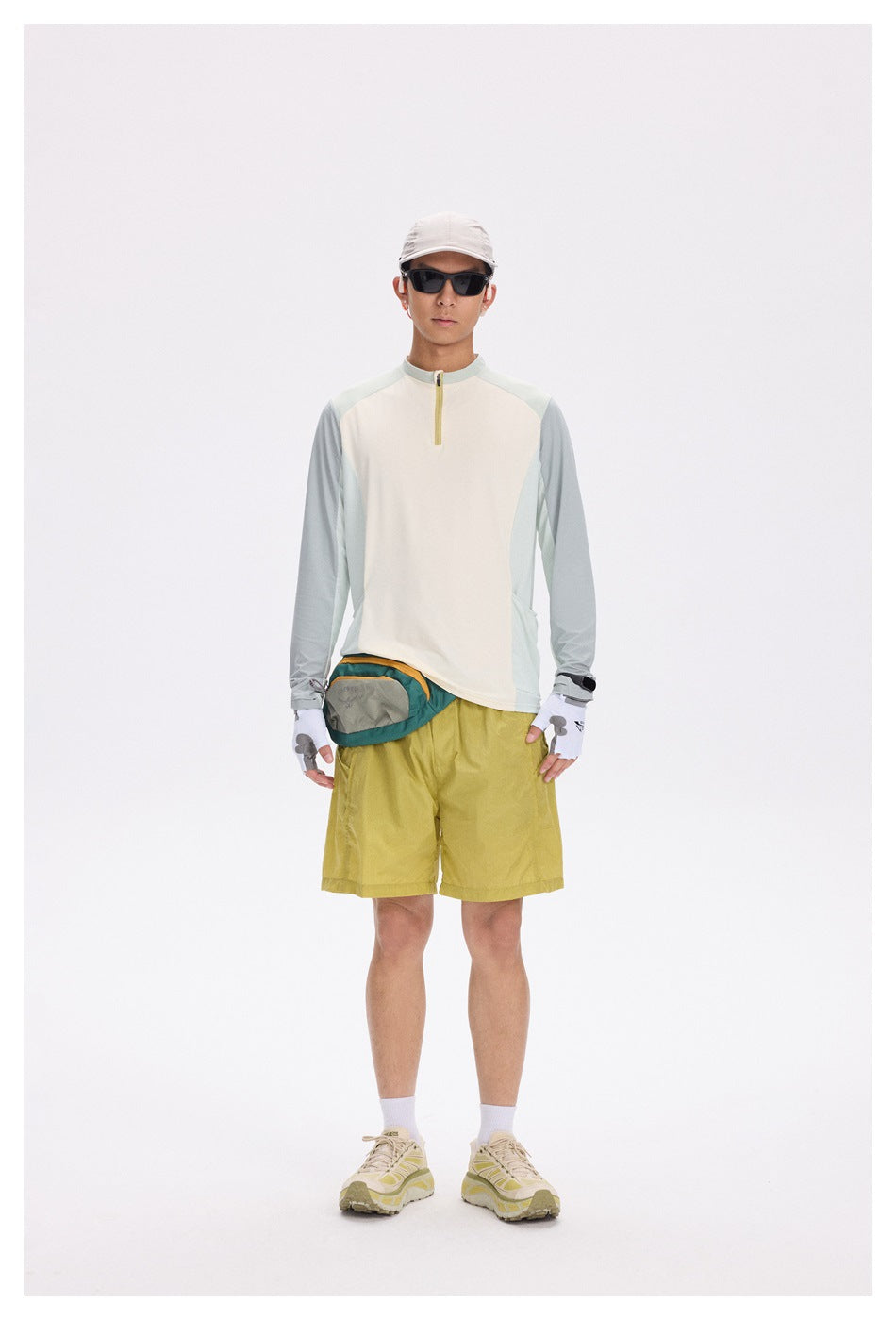 Model wearing the cream and sage green quarter-zip top with yellow shorts, front view