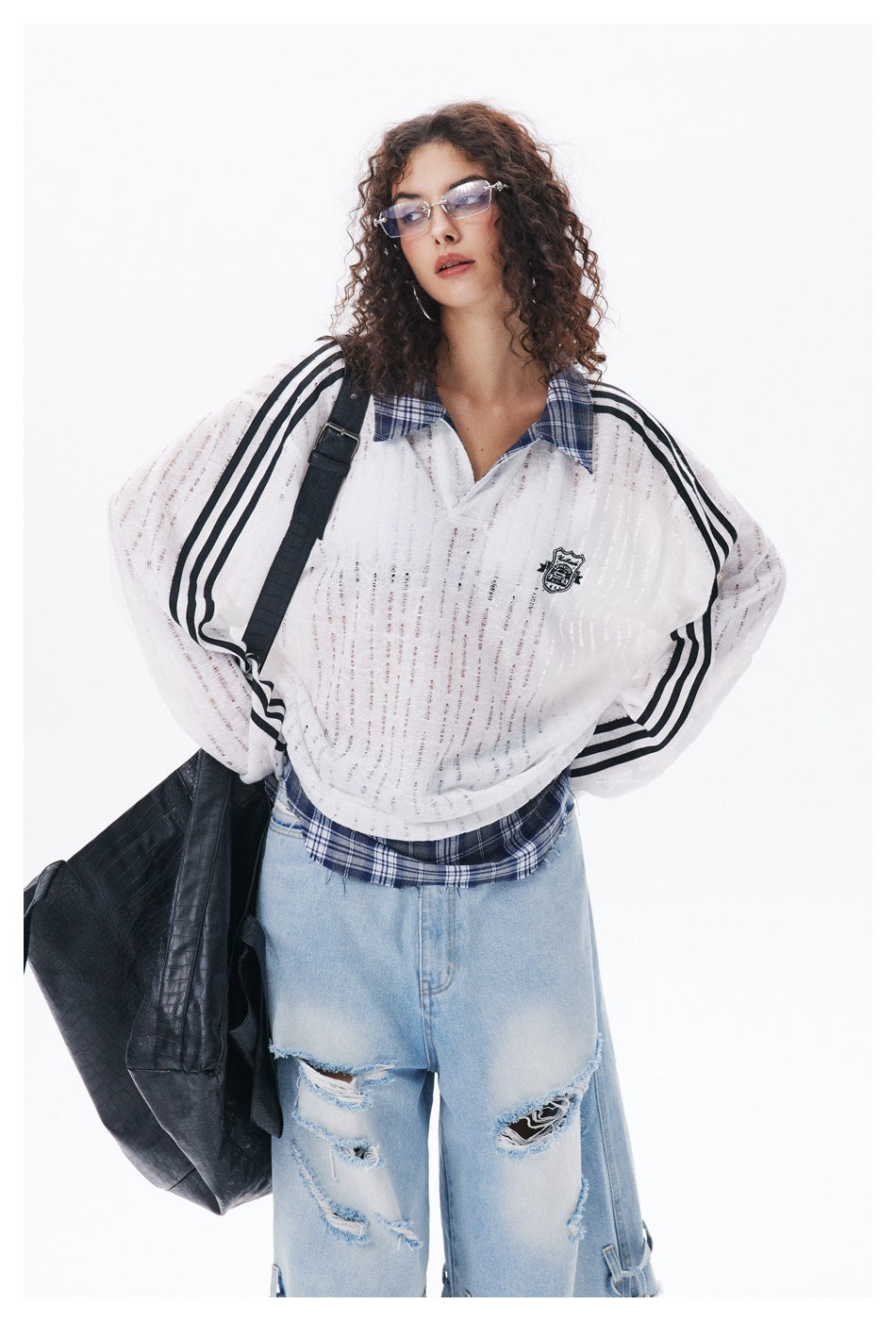Model wearing a white sheer long-sleeve top with black stripes and plaid collar, distressed light jeans, and a black shoulder