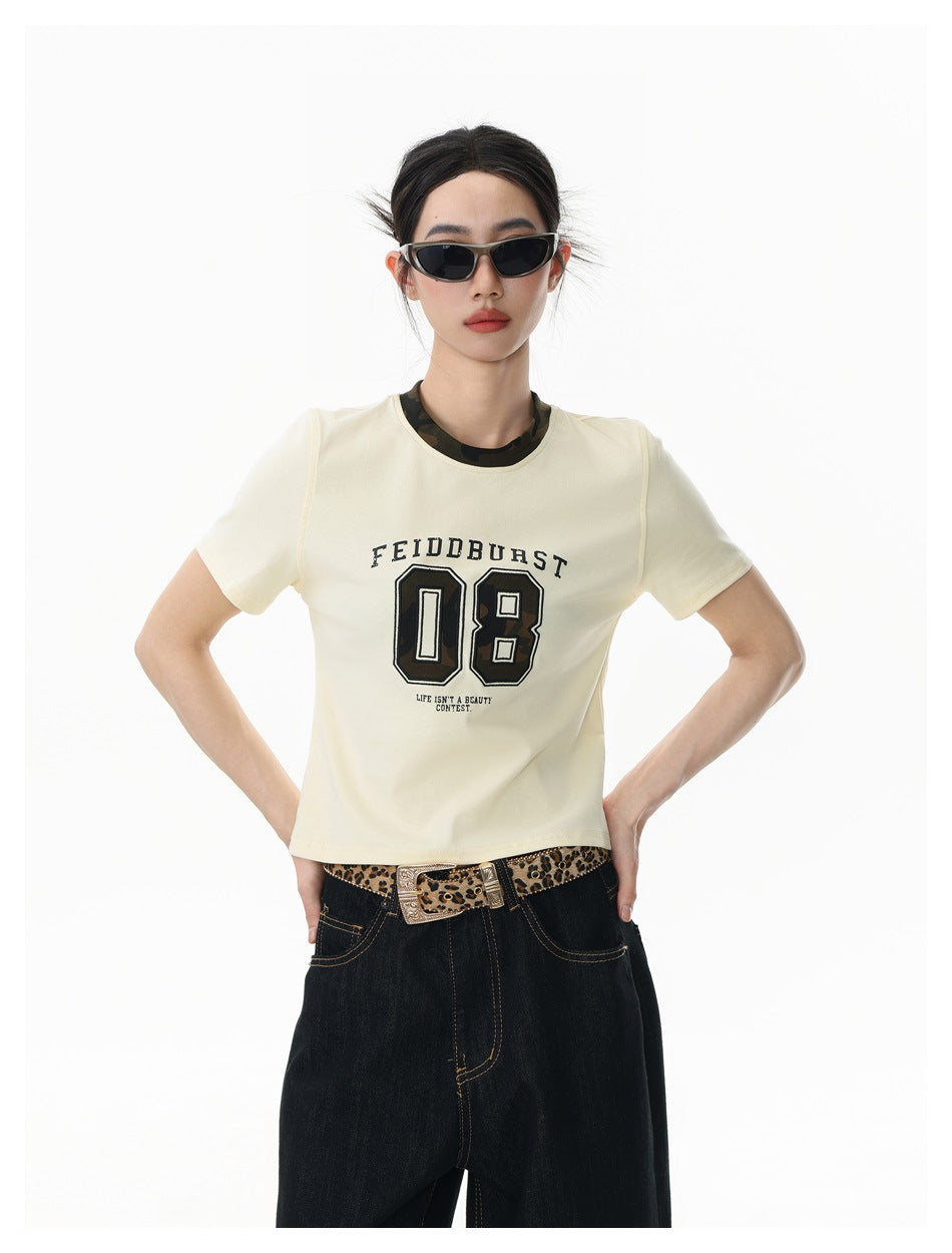 Front view of a model wearing an ivory graphic T-shirt with dark wide-leg jeans and a leopard-print belt.