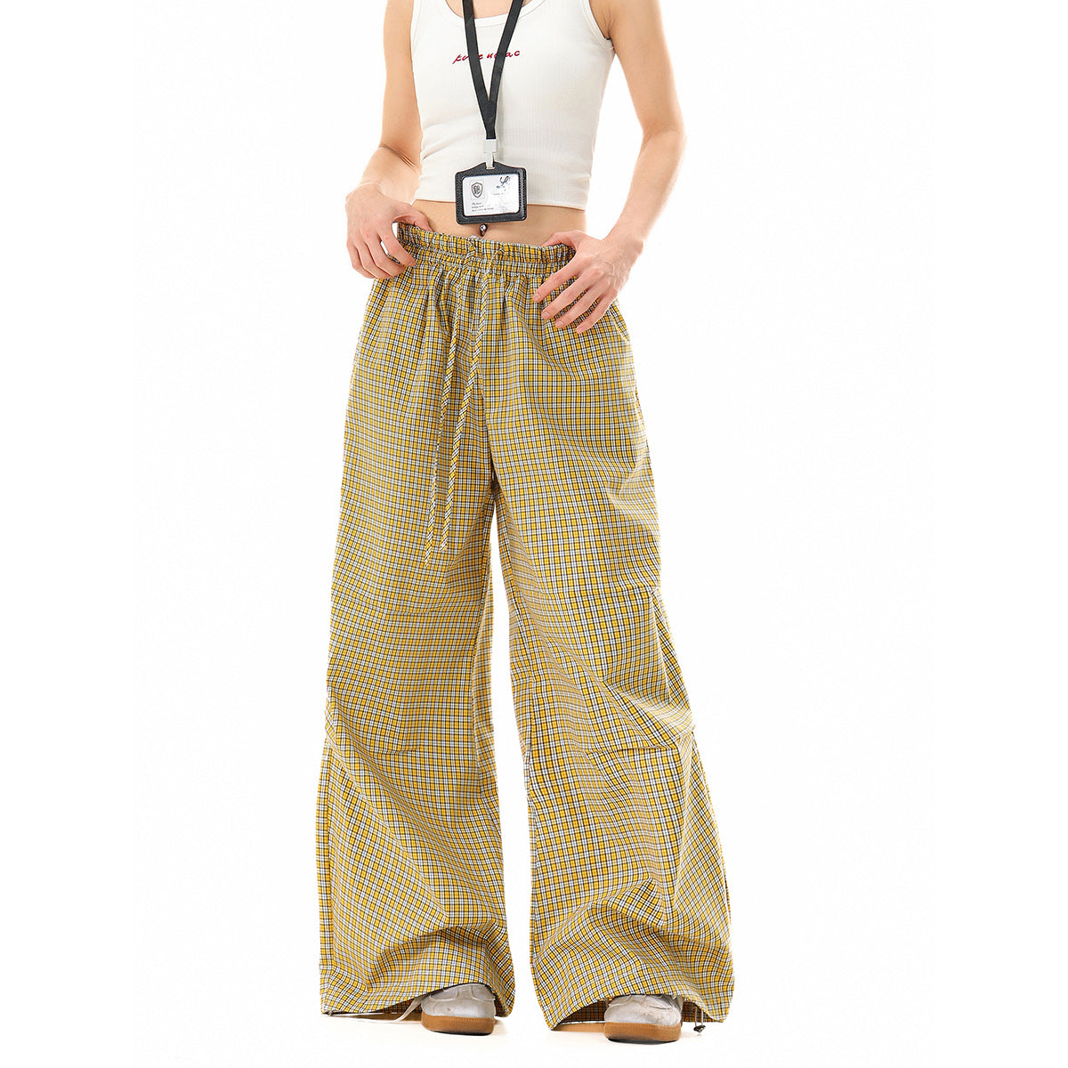 Front view of a model wearing wide-leg yellow, white and dark-check pants with an elastic drawstring waist.