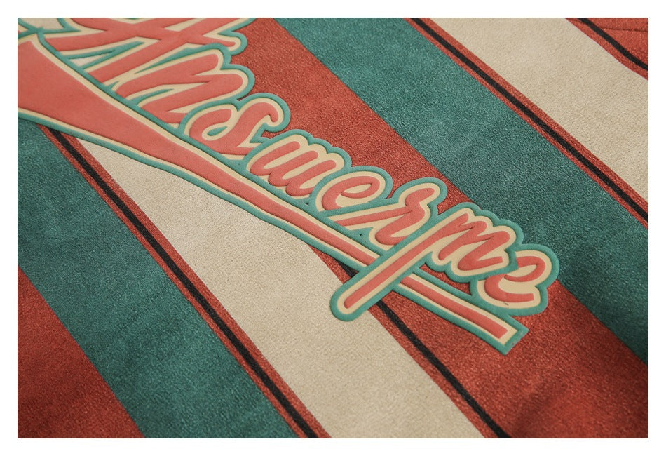 Close-up of raised coral script lettering with teal edging on a beige, teal, and rust striped garment.