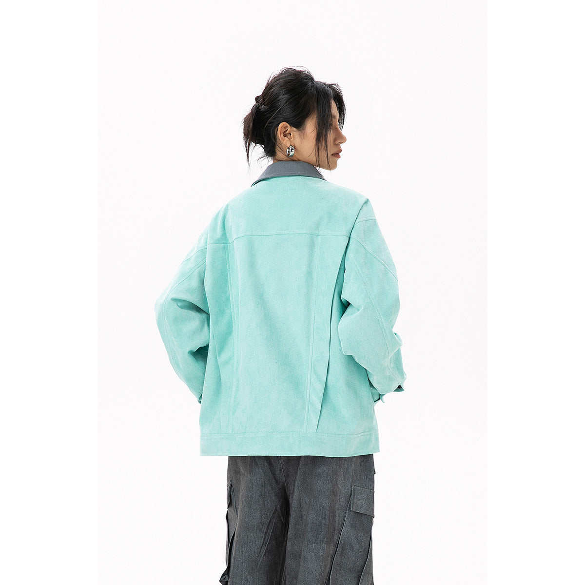 Back view of a model wearing a mint jacket with a gray collar and charcoal cargo pants.