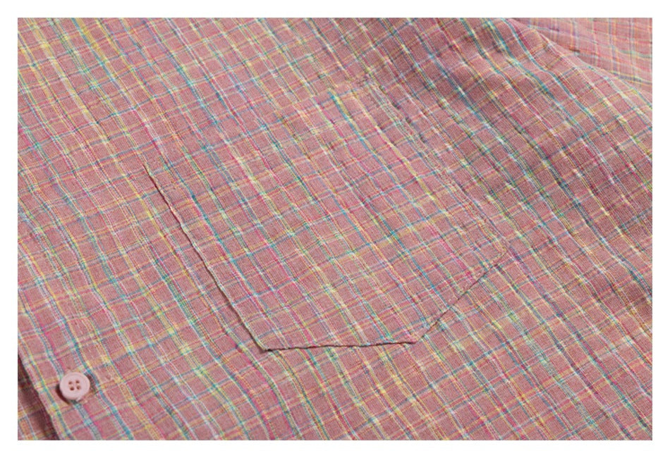 Close-up of a patch pocket on pink plaid shirt fabric, with part of a pale pink button visible.