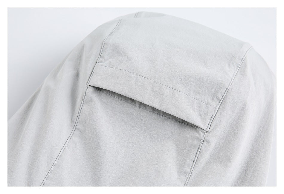 Close-up of a pale gray garment panel with a horizontal flap pocket and visible stitching.