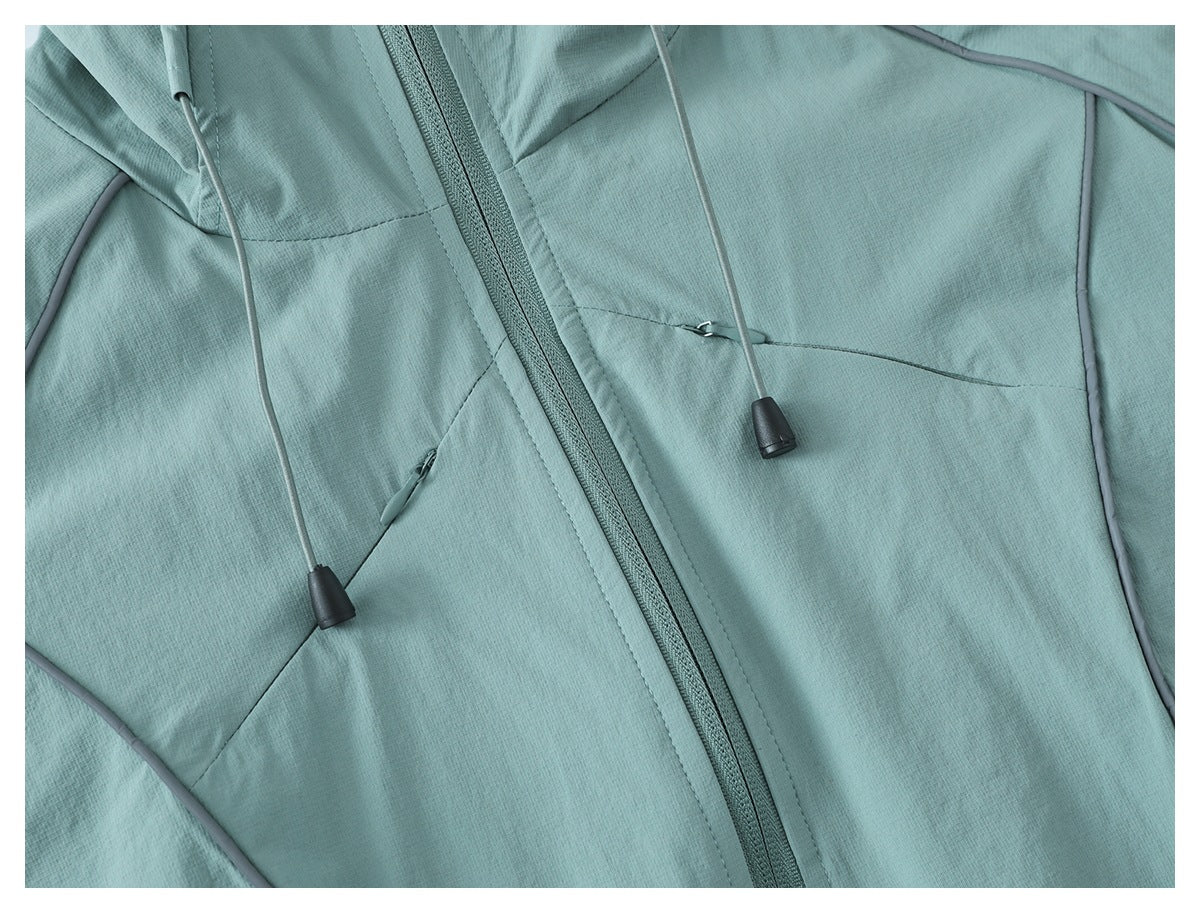 Close-up of a pale teal jacket front with a zipper, drawcords, and seam details.