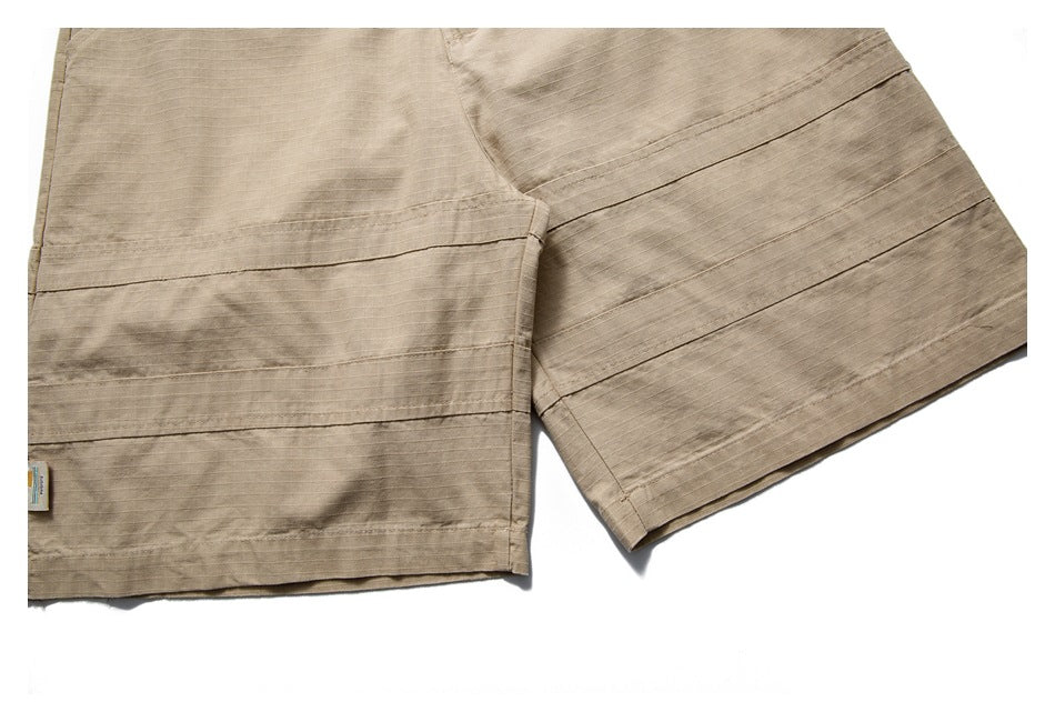 Cropped close-up of a tan garment's stitched hem and leg panel.
