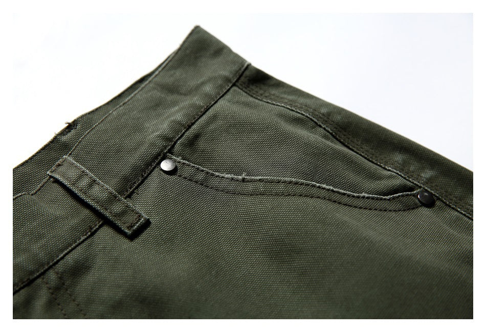 Close-up of an olive green trouser pocket with curved seams and metal rivets.