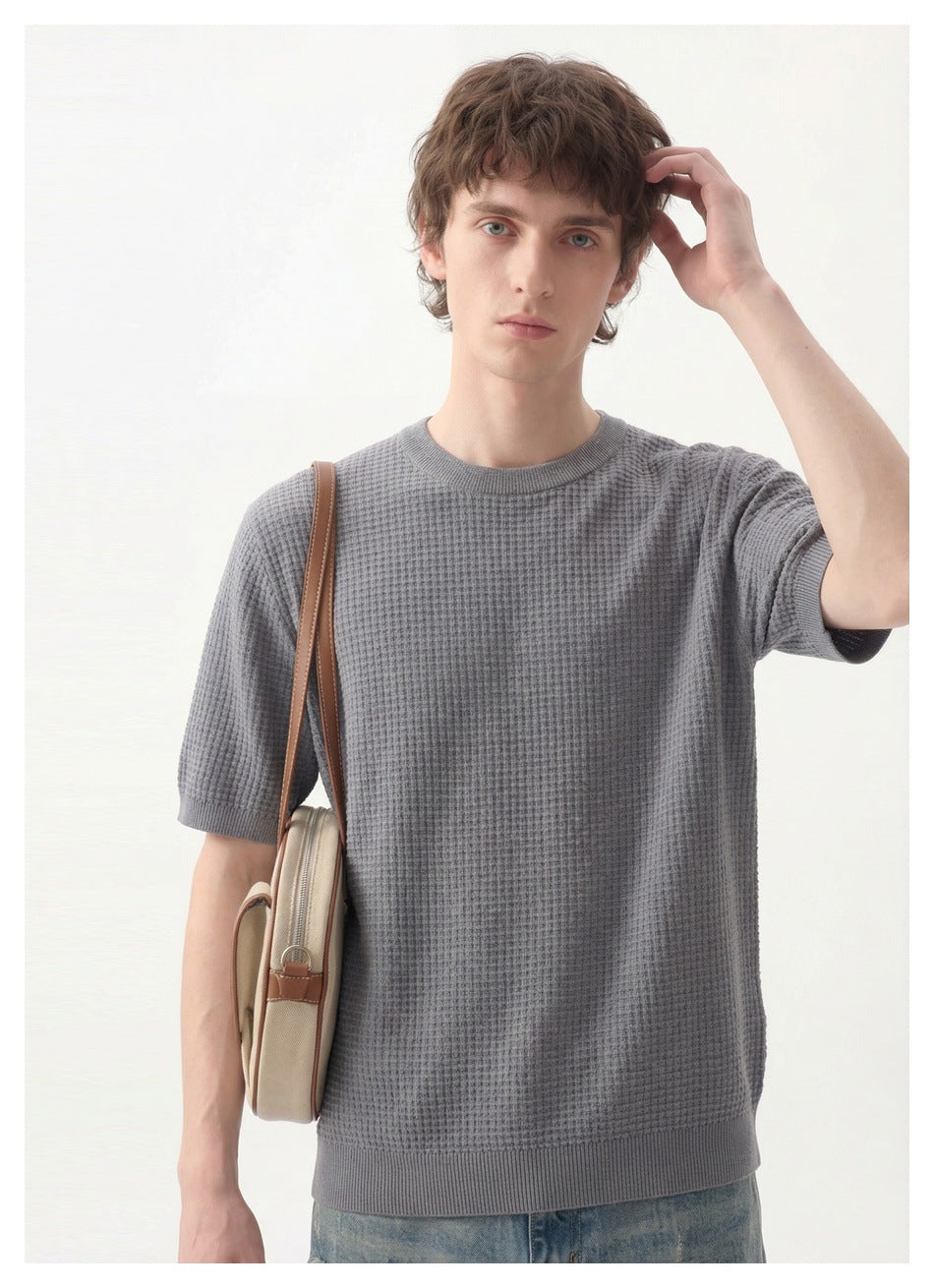 Close view of a model wearing a gray textured short-sleeve crewneck top with ribbed trim.