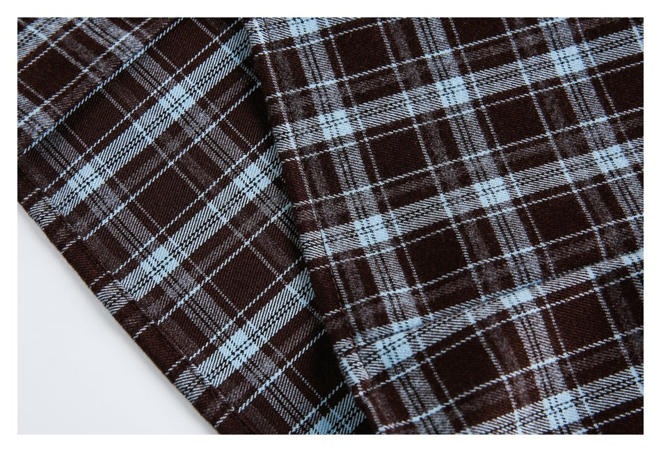 Close-up of plaid shirt fabric and a stitched seam in dark brown, pale blue, and white.