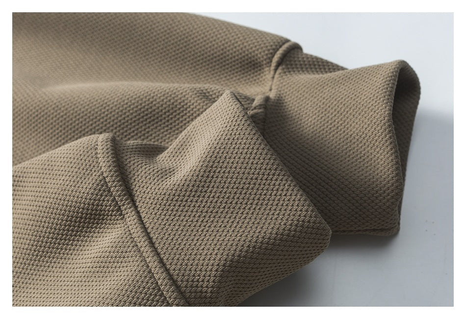 Close-up of folded taupe textured fabric showing a stitched edge and cuff-like fold.