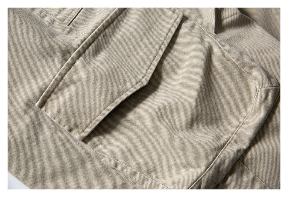 Close-up of a beige trouser pocket, flap, and visible diagonal weave.