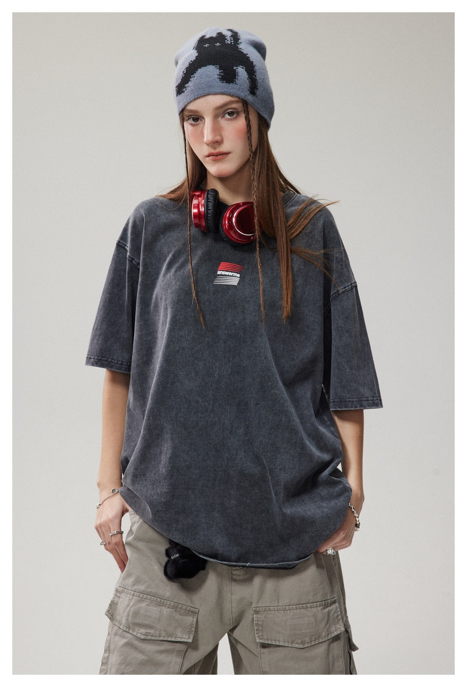 Front view of a model wearing an oversized charcoal washed T-shirt with a small red-and-white chest graphic.