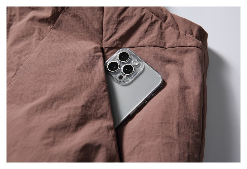 Close-up of a phone tucked into the vest's side pocket, showing the pocket opening and stitching.